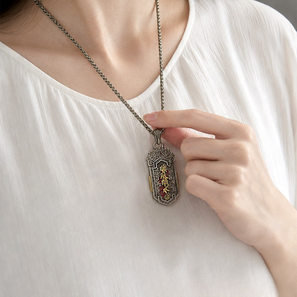 Model wearing the double koi copper pendant showing the calligraphy side with gold Smooth Sailing characters and red enamel, held near the chest on a silver chain